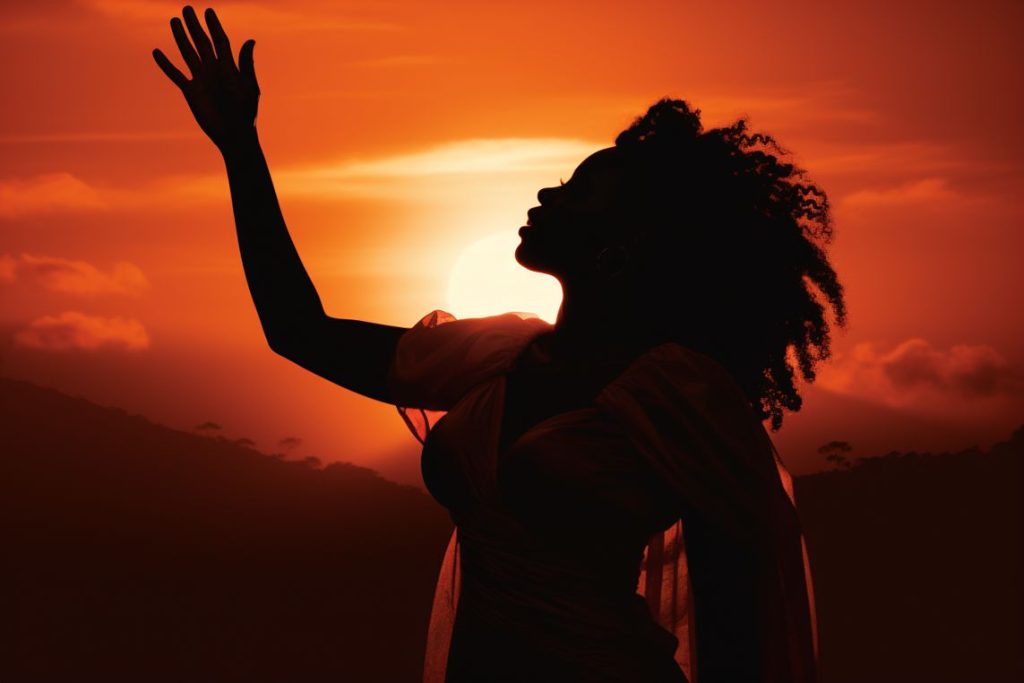 alt text: "silhouette of a confident african american woman raising her hand towards the sunrise" (keyword: african american woman)